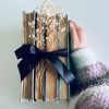 A stack of vintage books tied with a black ribbon and adorned with delicate flowers, held by a hand.